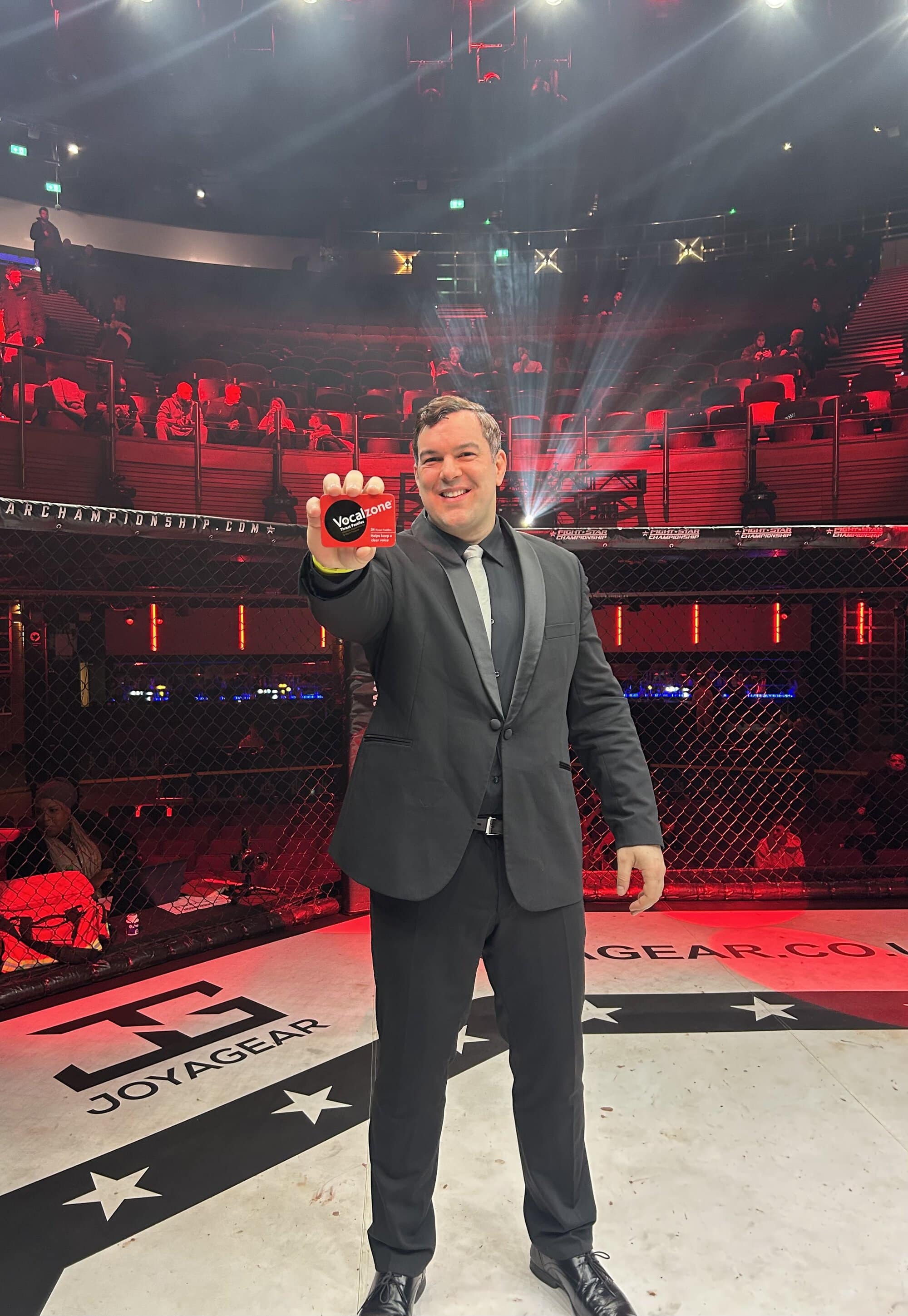 Dean Middhat stood in the middle of a boxing ring holding up to the camera a packet of Original Vocalzone Pastilles